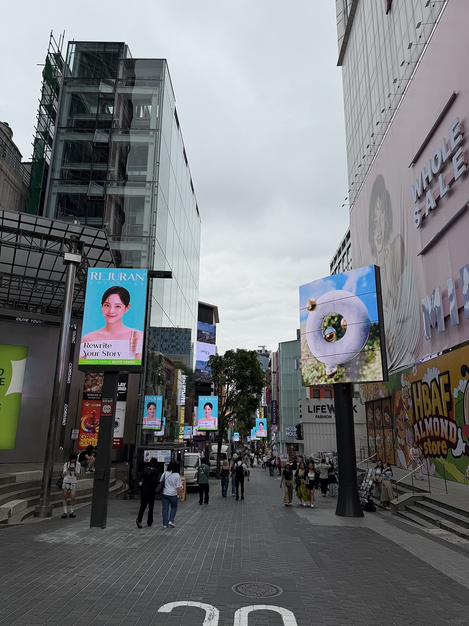 Pedestrians walking between shopfronts on a central Myeongdong shopping street